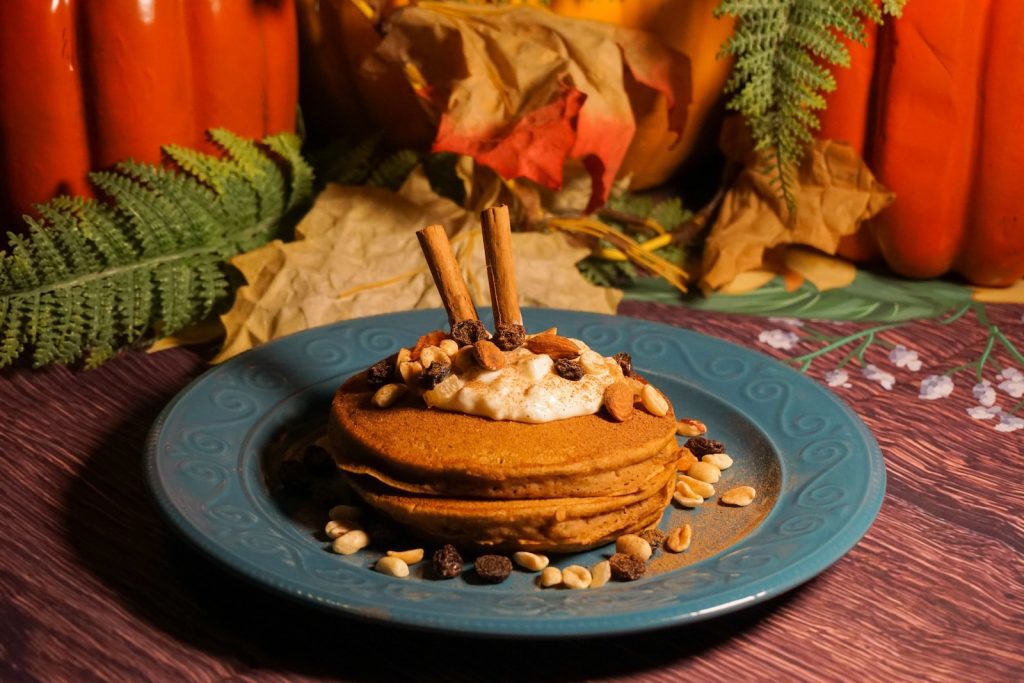 a blue plate topped with a stack of pancakes covered in whipped cream